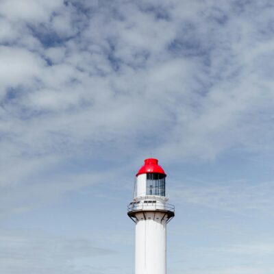 Beacon on shore under cloudy sky in daylight