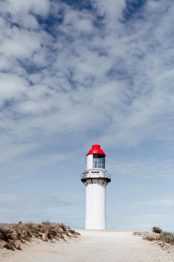 Beacon on shore under cloudy sky in daylight