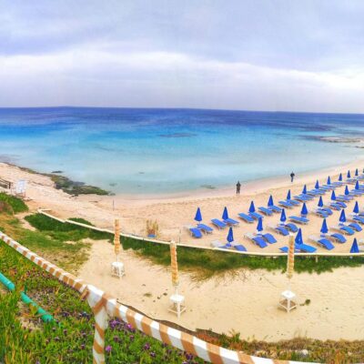 Bright endless ocean with many loungers on beach under sky