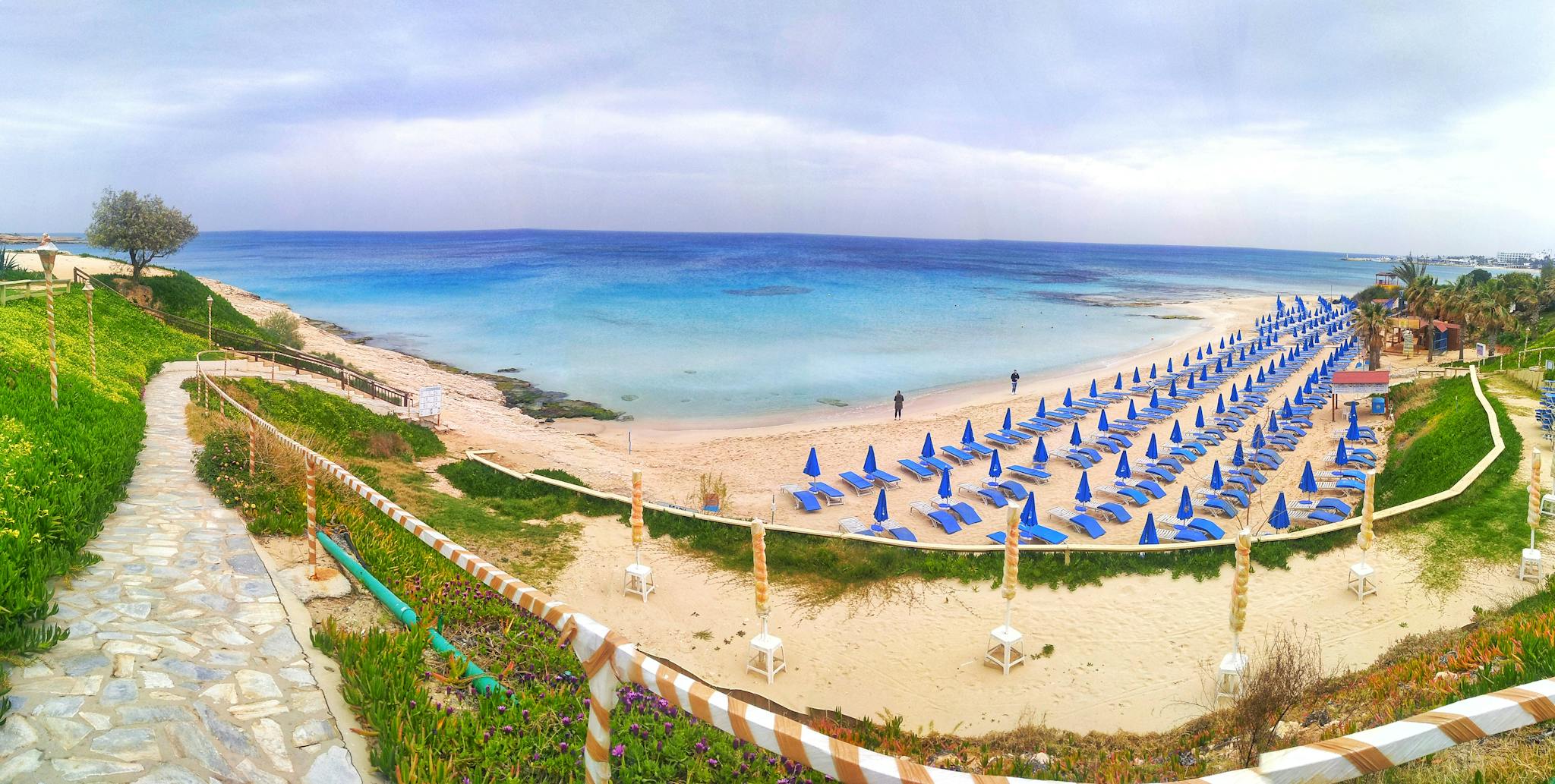 Bright endless ocean with many loungers on beach under sky